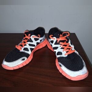 A pair of Nike Free Run 2. They Are Black With Orange Accents. Womens Size 6.5